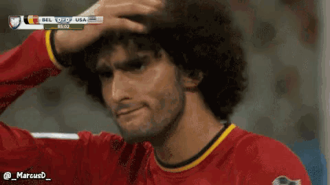 a man in a red shirt holds his hand to his forehead during a soccer game between belgium and the usa