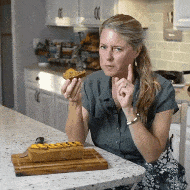 a woman is sitting at a counter eating a piece of food