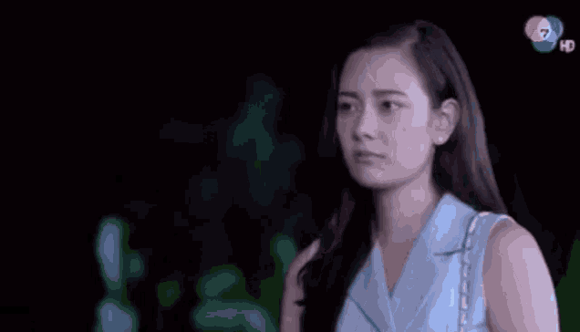 a woman is crying while standing next to a man in a dark room .