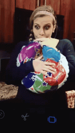 a woman is holding a bunch of balloons in her hands and covering her mouth with her hand