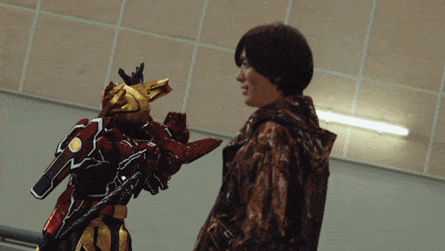a man standing next to a robot with a red and gold costume