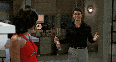 a woman in a red dress stands next to a man in a black shirt