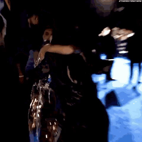 a woman in a black dress is dancing in a dark room with the words ethenextbigthing written on the bottom