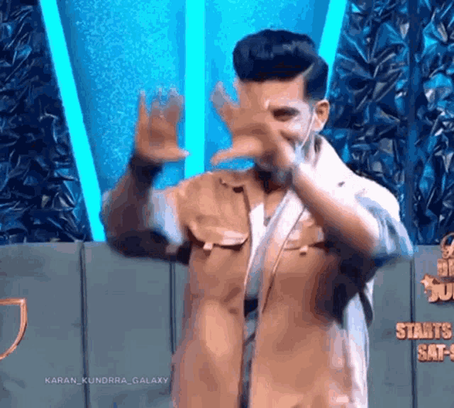 a man covering his face with his hands while standing in front of a sign that says starts sat 9