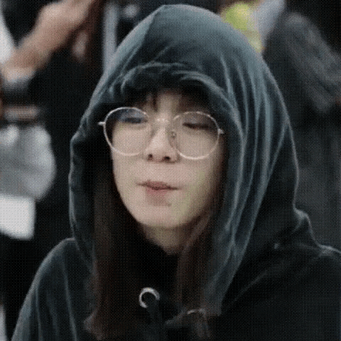 a woman wearing glasses and a hooded jacket is making a funny face .