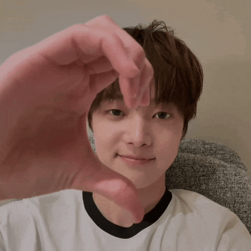 a young boy is making a heart shape with his hands