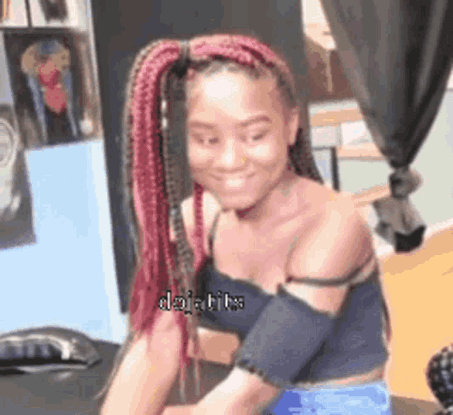 a woman with red braids is smiling and wearing a black tank top .