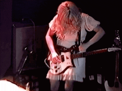 a woman is playing a guitar in a dark room