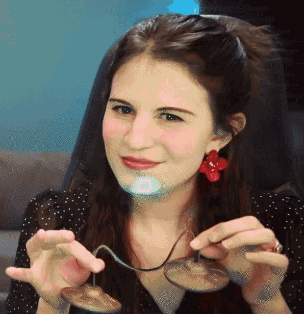 a woman with red earrings is holding a spoon