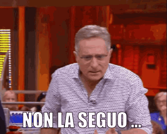 a man with glasses says non la seguio in front of a group of people