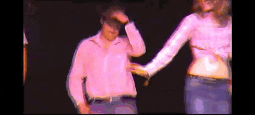 a man in a pink shirt is being touched by a woman in a pink top .