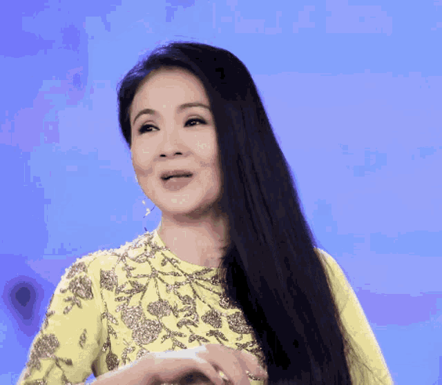 a woman with long black hair is wearing a yellow shirt