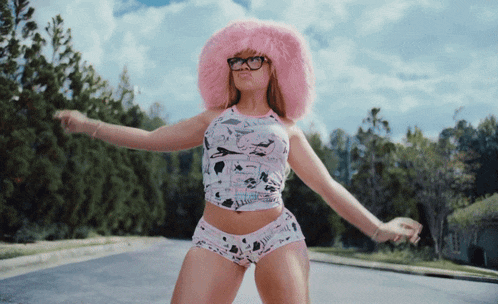 a woman wearing a pink hat and glasses is dancing on the street