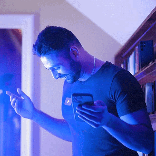 a man in a blue shirt is using a cell phone