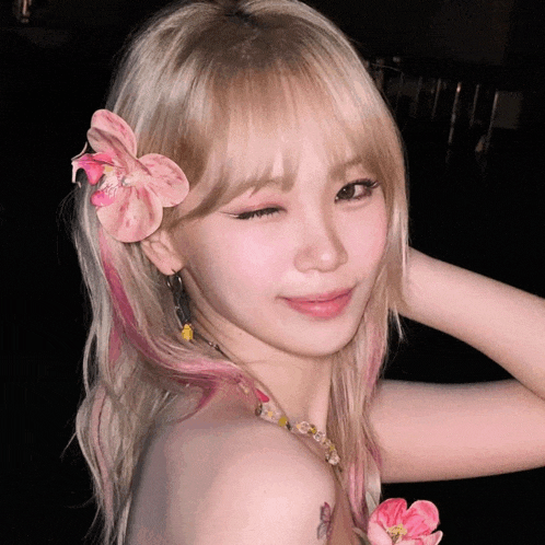 a woman with blonde hair and pink highlights has a flower in her hair