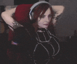 a woman is sitting in a chair wearing headphones and chains .