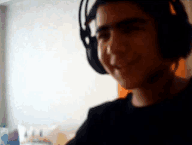 a young boy wearing headphones is smiling in a blurry photo