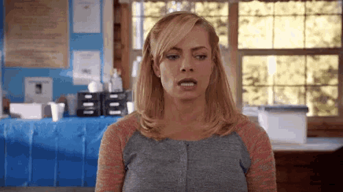 a woman with blonde hair is making a funny face in a room .