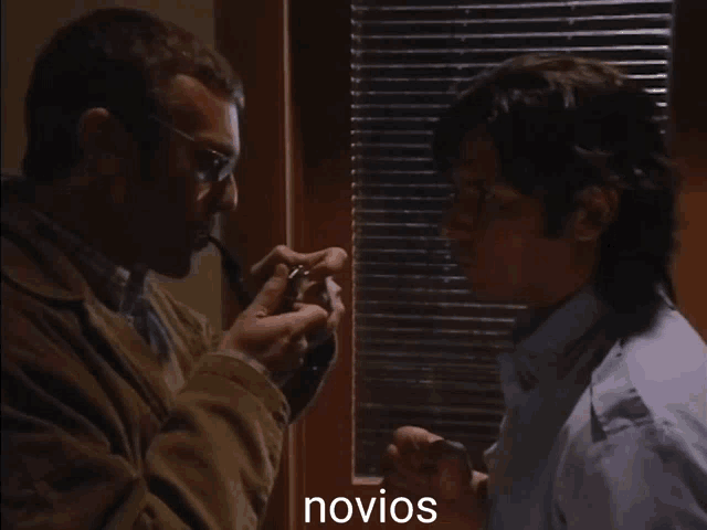 a man smoking a pipe next to another man with the word novios written on the bottom