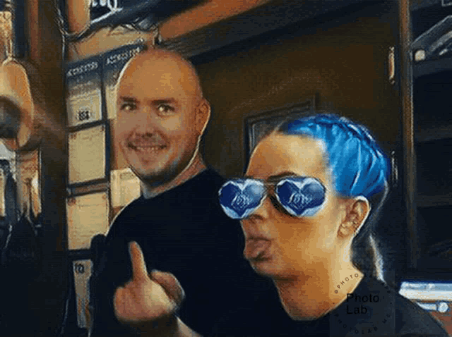 a man and a woman are posing for a picture and the woman has blue hair and sunglasses on