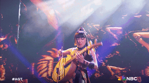 a woman playing a guitar on a stage with the nbc logo