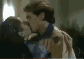 a man and a woman are kissing in a dark room