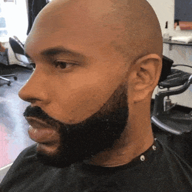 a man with a beard is sitting in a chair in a barber shop
