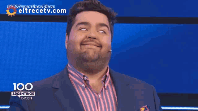a man in a suit is smiling in front of a screen that says 100 argentinas dien