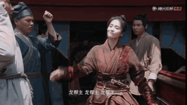 a woman in a kimono is dancing in front of a group of people with chinese writing on their faces