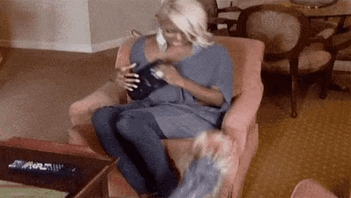 a woman is sitting in a chair in a living room holding a book .