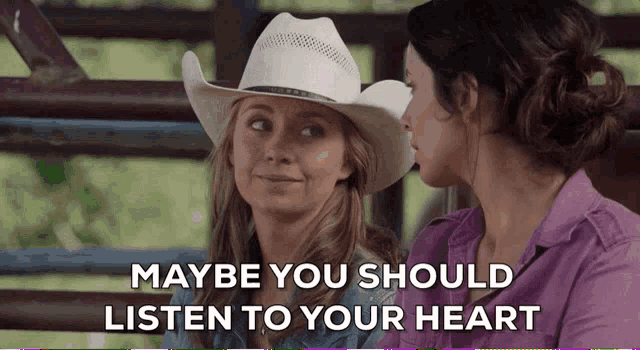 two women in cowboy hats are sitting next to each other with the words maybe you should listen to your heart above them
