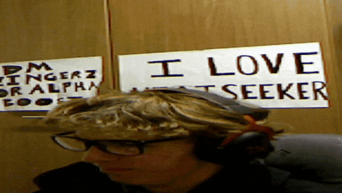 a man wearing headphones sits in front of a sign that says " i love seeker "