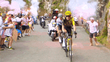 a group of cyclists are riding down a road in front of a crowd of people