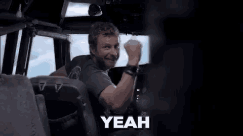 a man is standing in a crowd of people on an airplane and says yeah .