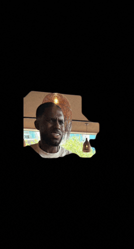 a man with a beard is standing in front of a window with a light hanging from the ceiling