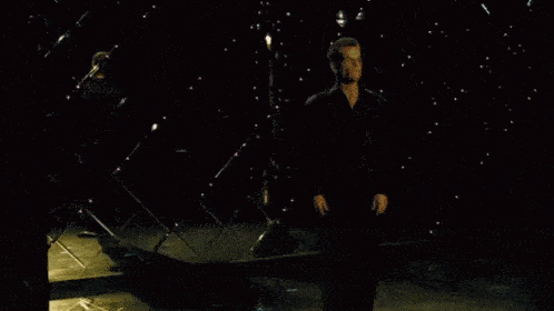 a blurry picture of a person standing in a dark room with a sword .