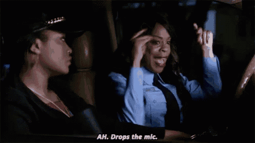 a woman in a police uniform is sitting in a car with another woman and says `` ah drops the mic '' .