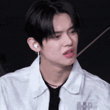 a young man wearing ear buds and a white jacket that says a.p.e.