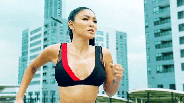 a woman in a bikini top is running in front of tall buildings