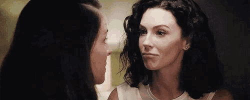 two women are looking at each other and making a face .