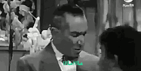 a man in a suit and tie talks to another man in a black and white photo
