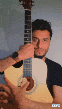 a man playing an acoustic guitar with xefx written on the bottom right