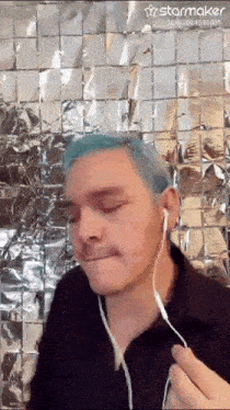 a man with blue hair is wearing headphones and a mustache .