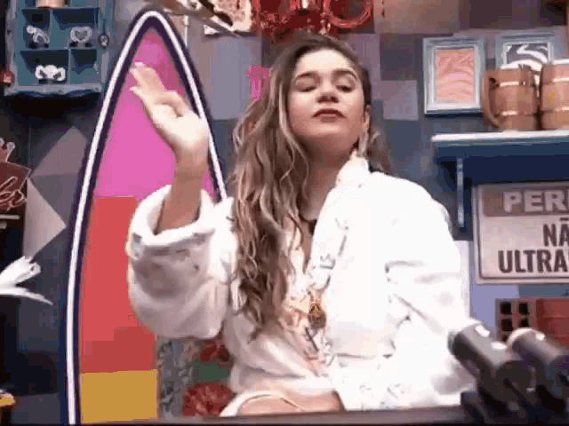 a woman in a bathrobe is holding a gun in front of a sign that says per na ultra .