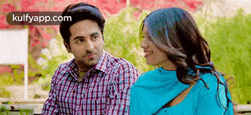 a man and a woman are looking at each other while sitting next to each other .