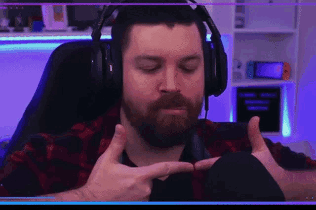 a man with a beard is wearing headphones and making a peace sign .