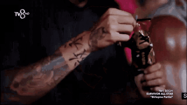 a man with a tattoo on his arm is holding a bag that says ' survivor all star ' on the bottom