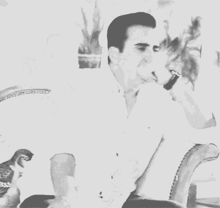 a man is sitting in a chair smoking a cigarette .