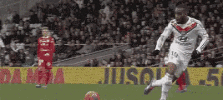 a soccer player kicking a ball on a field with a sign that says juso