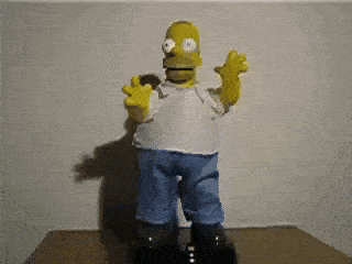 a homer simpson toy is standing on a table with his arms outstretched